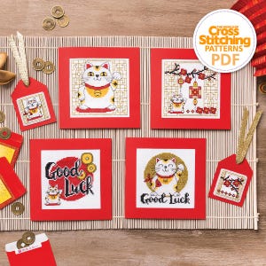 Peut inclure: Plusieurs motifs de point de croix avec des chats porte-bonheur, présentés sur des cartes et étiquettes rouges. Les motifs incluent le texte "Good Luck" et des motifs chinois traditionnels. L'image contient également le texte "The World of Cross Stitching Patterns PDF".