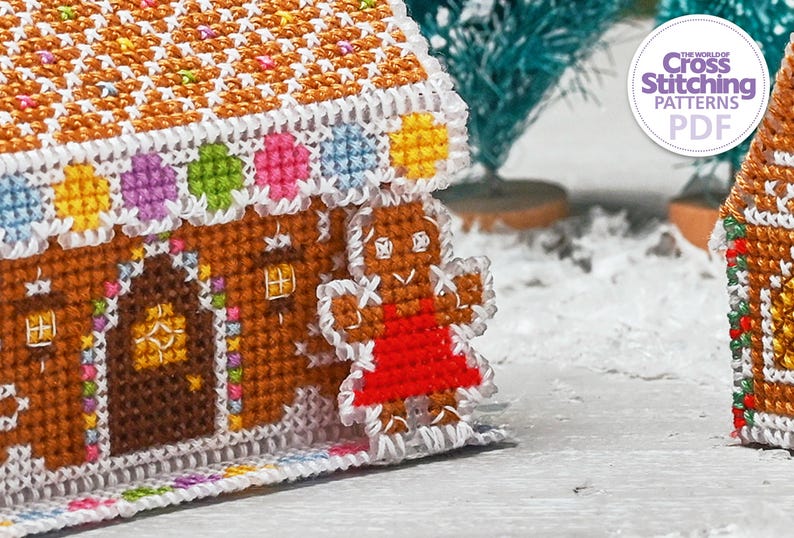 May include: A gingerbread house cross stitch pattern with a gingerbread person standing in front of it. The house is decorated with colorful candies and the gingerbread person is wearing a red dress. The pattern is from The World of Cross Stitching Patterns PDF.