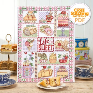 May include: A cross stitch pattern featuring a colorful patchwork design of various sweet treats, including cakes, cupcakes, donuts, ice cream, and a mug with a flower. The text "Life is Sweet!" is centered in the design.