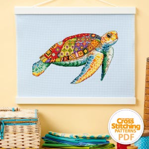 Może przedstawiać: Kolorowy wzór do haftu krzyżykowego przedstawiający żółwia morskiego z patchworkową skorupą. Wzór jest oprawiony i gotowy do haftowania. Obraz zawiera również tekst "The World of Cross Stitching Patterns PDF".