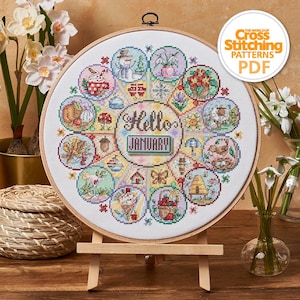 May include: A cross-stitch pattern in a wooden hoop, featuring a circular design with seasonal illustrations. The center reads "Hello January." The design includes images of a snowman, flowers, and other seasonal elements. The text "The World of Cross Stitching Patterns PDF" is in the upper right corner.