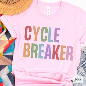 May include: Pink t-shirt with the text "CYCLE BREAKER" in rainbow colors.