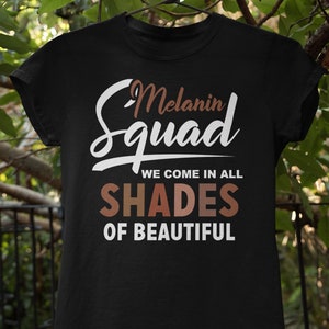 May include: Black t-shirt with white text that reads "Melanin Squad We Come In All Shades Of Beautiful". The text "Shades" is in rainbow colors.