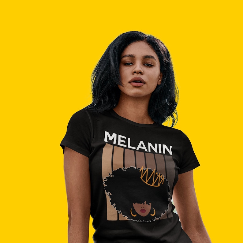 May include: A black t-shirt with the word "MELANIN" printed in white letters. The shirt features a graphic of a brown-skinned woman with a crown and afro hair.