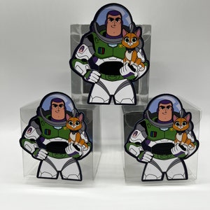 May include: Three clear plastic boxes featuring a cartoon image of Buzz Lightyear from Toy Story holding a small orange cat. The boxes are on a white surface.