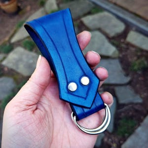 May include: A blue leather belt loop with two silver rivets and a silver metal ring.