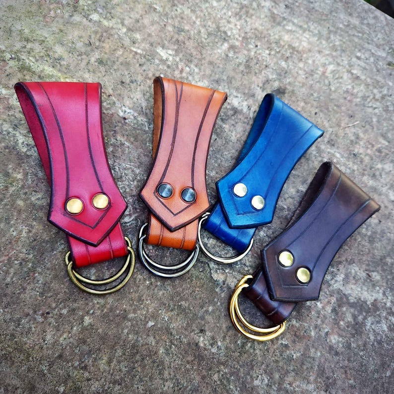 May include: Four leather belt loops with metal rings. The loops are in red, brown, blue, and dark brown.