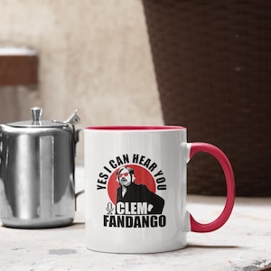 May include: White ceramic mug with a red interior and handle. The mug features a graphic of a man with sunglasses and the text "YES I CAN HEAR YOU CLEM FANDANGO" in black and red.
