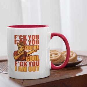 Könnte beinhalten: Weiße Keramik-Tasse mit rotem Innenraum und Henkel. Die Tasse zeigt eine Grafik eines Mannes mit Krone, der zeigt, mit dem Text "F*CK YOU, YOU'RE COOL, I AM OUT."