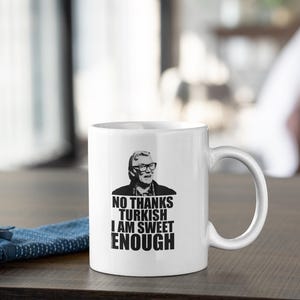 May include: White ceramic mug with a black and white image of a man with glasses and the text "NO THANKS TURKISH I AM SWEET ENOUGH".