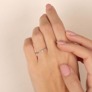 May include: A delicate silver ring with a small, clear gemstone in the center and smaller gemstones on either side.