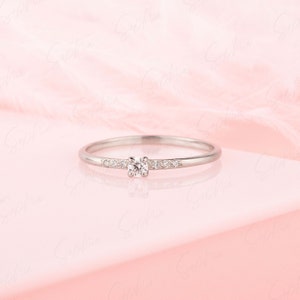 May include: A delicate silver band ring with a single round diamond and smaller diamonds set along the band.