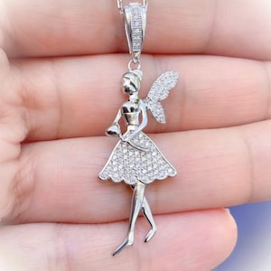 May include: A silver pendant necklace featuring a detailed fairy figurine with wings and a sparkling crystal-like finish.