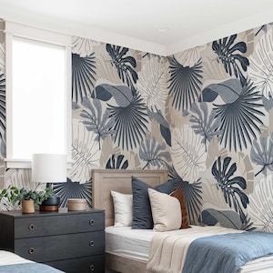 May include: A bedroom with two twin beds, a dark gray dresser, and a window. The beds have blue and beige bedding and pillows. The walls are covered in a tropical leaf pattern wallpaper in shades of gray, blue, and beige.