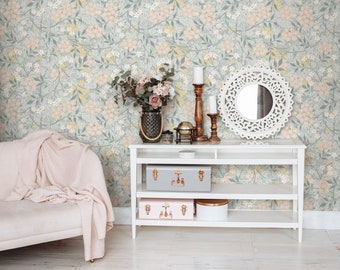 May include: A white shelf unit with three shelves, featuring a white decorative mirror with a carved design, two candlesticks, a globe, and two decorative boxes. The shelf unit is in front of a wall with a floral wallpaper pattern in shades of green, pink, and yellow.
