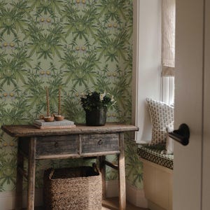 Peut inclure: Une console en bois rustique avec deux tiroirs et un panier tressé en dessous. La table est ornée de livres, de bougies et d'un vase de fleurs. Le fond présente un papier peint floral vert.