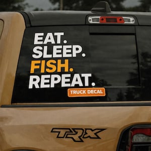 Puede incluir: Calcomanía negra para ventana de camión con las palabras "EAT. SLEEP. FISH. REPEAT." en letras blancas y naranjas. Las palabras están apiladas verticalmente. La calcomanía también incluye el texto "TRUCK DECAL" en un rectángulo naranja.