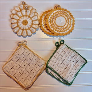 May include: A collection of eight handmade crochet potholders in four distinct styles. Two are flower-shaped with white and yellow yarn, two are circular with yellow and white patterns, two are square with yellow trim, and two are square with green trim.