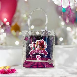 Puede incluir: Bolsa de regalo de plástico transparente con adornos de estrella y corazón plateados. La bolsa presenta un gráfico colorido de tres mujeres, el nombre "Sophia" y el número "5". Tiene un asa transparente.