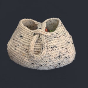 May include: A crocheted cream-colored bag with black flecks. The bag has a drawstring closure and a handle.