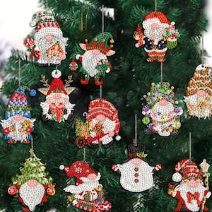 May include: A collection of Christmas ornaments shaped like gnomes, each with unique designs and colors. The ornaments are decorated with various patterns and embellishments, including hats, beards, and festive attire. They are hanging on a green Christmas tree.