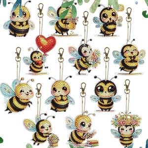 May include: A collection of bee-shaped keychains with various designs. Each keychain features a yellow and black bee with different accessories, including a heart balloon, flowers, and a floral crown. They have silver-colored clasps.