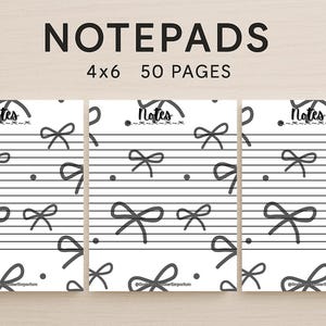 May include: Three notepads with a white background and a black bow and dot pattern. The word "Notes" is at the top, above the musical staff lines. The text "NOTEPADS 4x6 50 PAGES" is at the top.