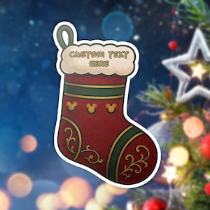 May include: A Christmas stocking sticker with a red base, green and gold accents, and the text "CUSTOM TEXT HERE". The stocking features Mickey Mouse head silhouettes and decorative swirls. A festive holiday decoration.