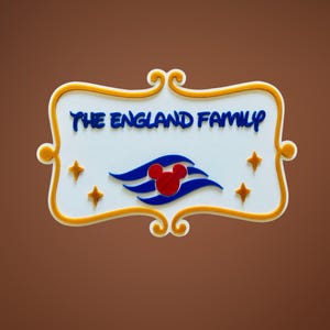 May include: A white rectangular sign with the text "THE ENGLAND FAMILY" in blue, framed by a gold border. The sign features a Mickey Mouse head logo and four gold stars. The background is a solid brown.