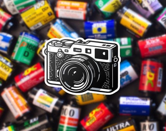 May include: A black and white illustration of a vintage film camera with a large lens. The camera is surrounded by a variety of colorful film canisters.
