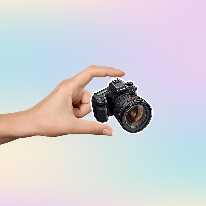 May include: A black Canon camera with a large lens, held in a hand.