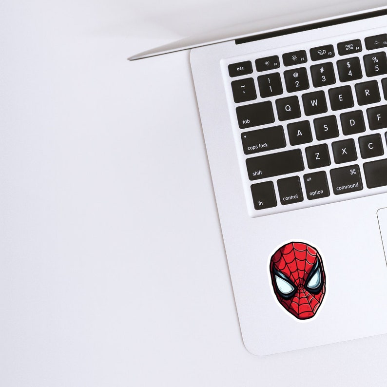 May include: A white laptop computer with a black keyboard and a red and black Spider-Man sticker on the bottom right corner.