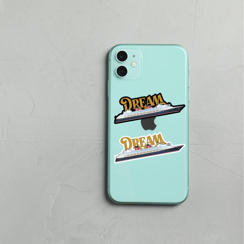 Puede incluir: Un iPhone 11 Pro azul claro con dos pegatinas de un crucero y la palabra "DREAM" en letras doradas. Las pegatinas son en blanco y negro con detalles en rojo y dorado. El tel&eacute;fono est&aacute; sobre una superficie gris claro.