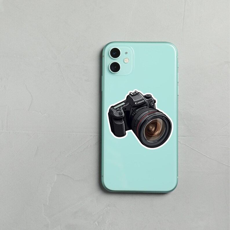 May include: A blue smartphone case with a black and silver camera sticker. The camera sticker has the word "Canon" on it.