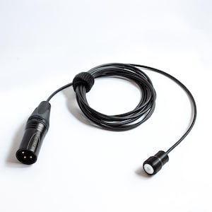May include: A black microphone cable with a coiled section secured by a black velcro strap. The cable has a male XLR connector on one end and a small microphone head on the other. The background is white.