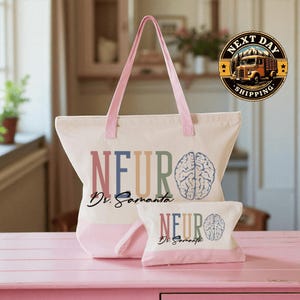 A pink tote bag with the text "NEURO Dr. Samanta" printed on it, along with a smaller bag or pouch that also has the same text. The bag is placed on a pink surface, and there is a logo for "Next Day Shipping" in the background.