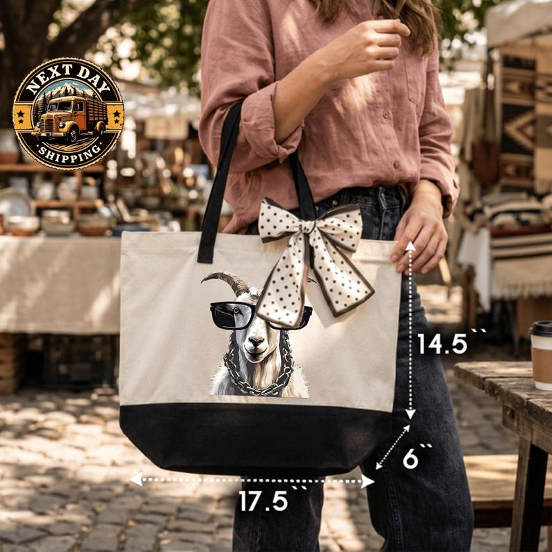 A woman is holding a large tote bag with a printed image of a goat wearing sunglasses and a chain.