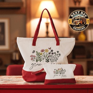 A large white tote bag with a red handle and a smaller white bag with a red handle, both featuring floral designs, are placed on a red surface.