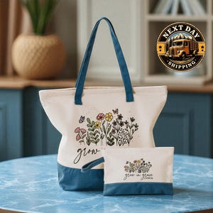 A white tote bag with a floral design and the word "grow" printed on it, along with a smaller white bag with a similar floral design and the word "grow" printed on it, both sitting on a blue marble surface.