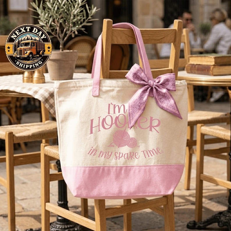 A pink tote bag with the text "I'm Hooper in my spare time" printed on it, sitting on a wooden chair.