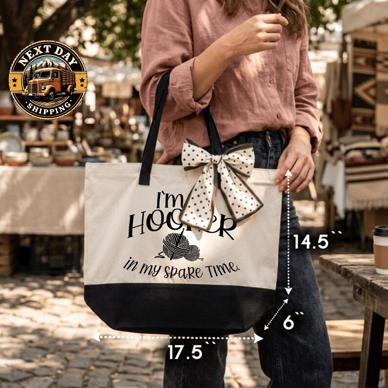 A woman is holding a large tote bag with a humorous text printed on it, standing in front of a market or outdoor setting.