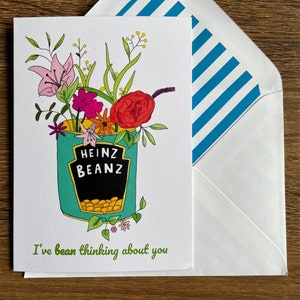 May include: Greeting card with a whimsical illustration of a Heinz Beanz can overflowing with flowers. The card reads "I've bean thinking about you." The envelope has blue and white stripes.