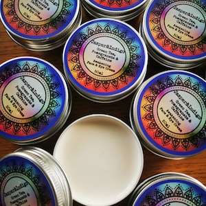 Pu&ograve; includere: Pi&ugrave; contenitori piccoli in argento con etichette colorate che riportano "Jasper & Indigo" e elencano gli ingredienti "T&egrave; verde, melograno e caffeina" e "Crema viso e occhi energizzante" con una dimensione di 50 ml.