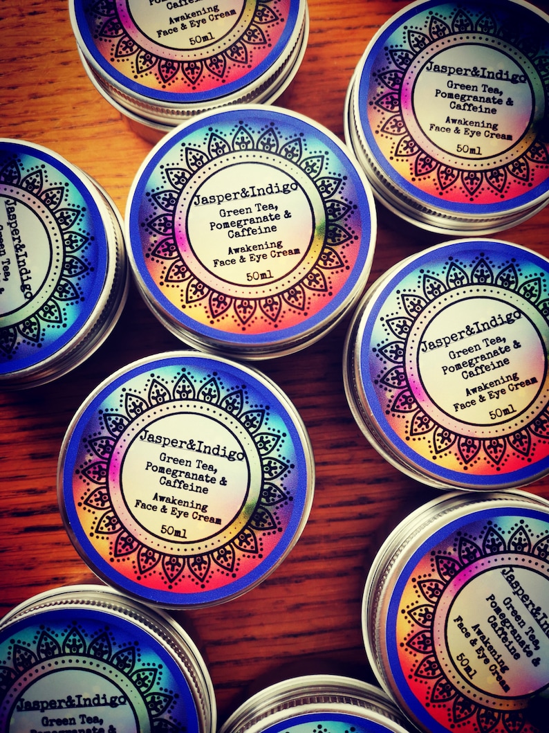 Pu&ograve; includere: Pi&ugrave; contenitori piccoli in argento con etichette colorate che recitano "Jasper&Indigo Green Tea, Pomegranate & Caffeine Awakening Face & Eye Cream 50ml".
