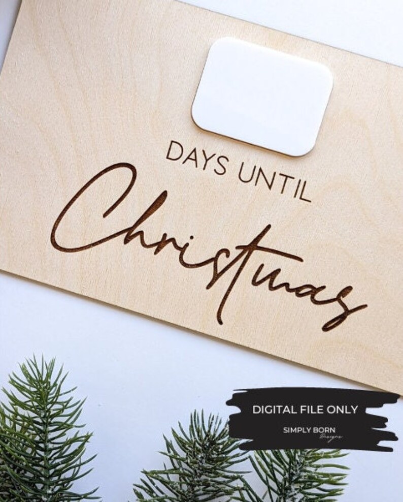 May include: A wooden sign with the text "Days Until Christmas" in a cursive font. The sign has a blank space for a number to be placed. The sign is on a white background.