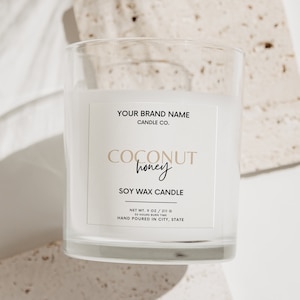 以下が含まれることがあります： 白いラベルに「YOUR BRAND NAME CANDLE CO. COCONUT honey SOY WAX CANDLE NET WT. 9 OZ / 211 G 38 HOURS BURN TIME HAND POURED IN CITY, STATE」と書いてある、透明なガラスのジャーに入ったキャンドルです。