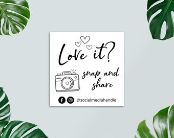 May include: White sign with black text that says "Love it? snap and share" with a camera icon and social media icons. The text also includes "@socialmediahandle".