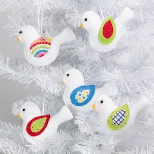 May include: Five white felt bird ornaments with colorful fabric wings. The birds are hanging on a white artificial Christmas tree.