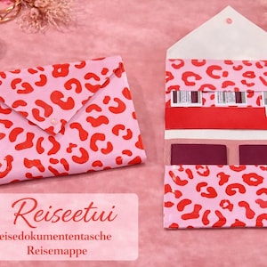 May include: Pink travel document holder with a red leopard print. The holder is open, revealing compartments for passports and tickets. A matching closed envelope is next to it. The text "Reiseetui" is on a label.