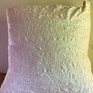 May include: White throw pillow with an embroidered floral pattern.